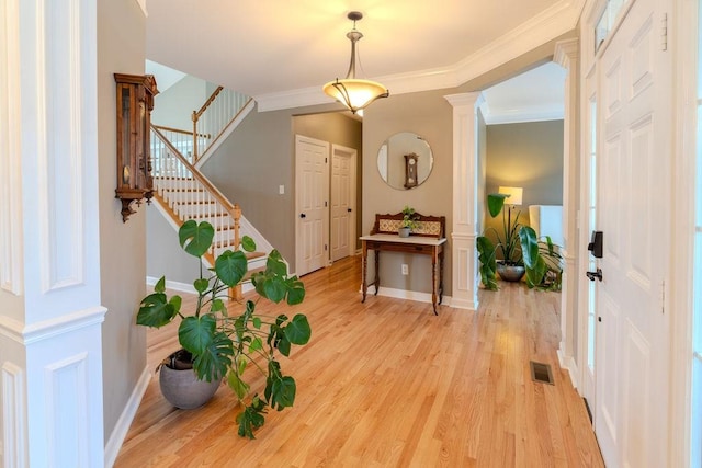 entryway featuring visible vents, crown molding, stairway, light wood-style flooring, and ornate columns