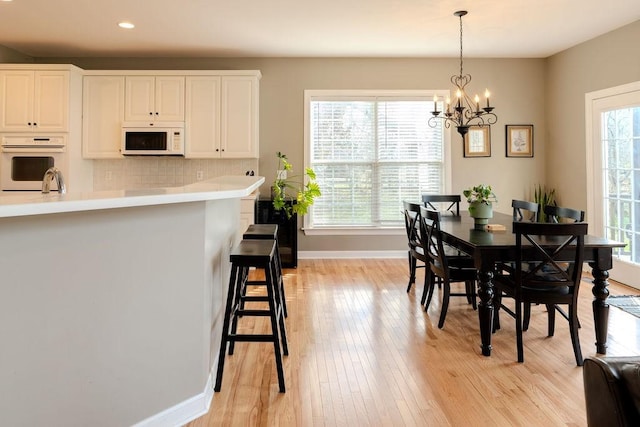 dining area with recessed lighting, baseboards, light wood-type flooring, and a chandelier