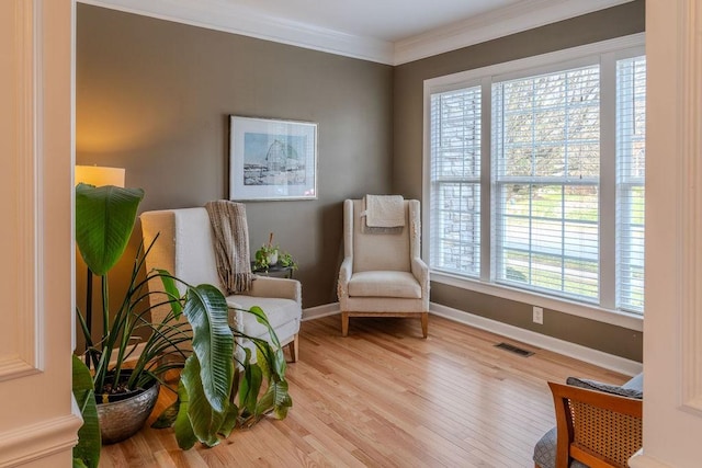 sitting room with visible vents, crown molding, baseboards, and wood finished floors