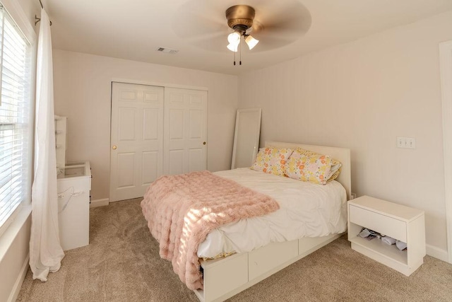 bedroom featuring a closet, multiple windows, light colored carpet, and visible vents