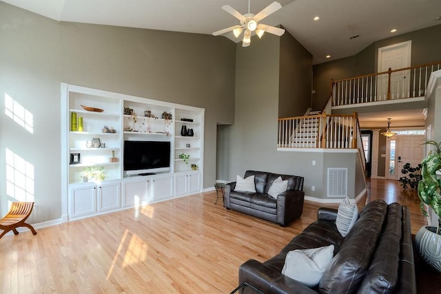 living room featuring visible vents, wood finished floors, stairway, baseboards, and a towering ceiling