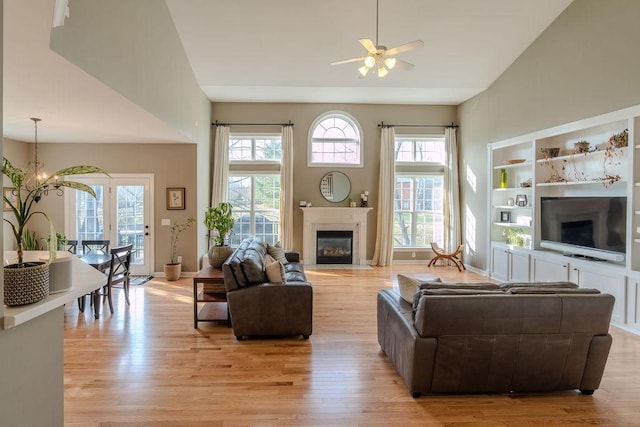 living area featuring light wood-type flooring, a fireplace with flush hearth, and baseboards