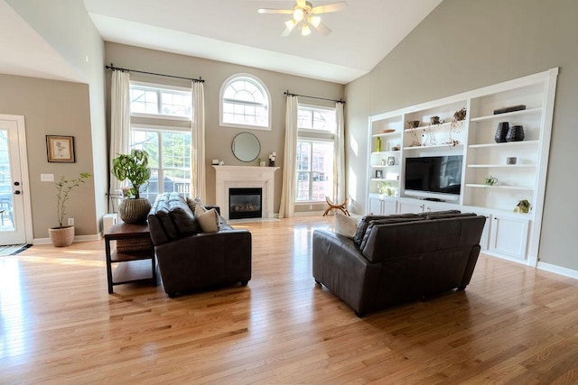 living room with a fireplace with flush hearth, light wood-style flooring, high vaulted ceiling, and baseboards