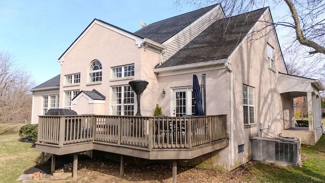 back of property featuring central air condition unit, brick siding, a deck, and a shingled roof