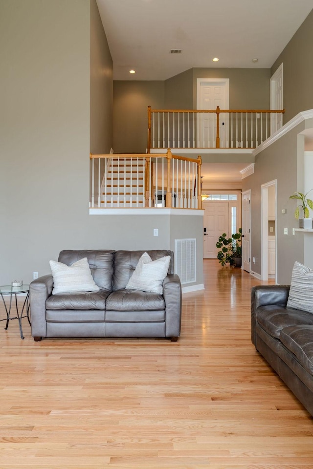 living area with stairs, a high ceiling, wood finished floors, and visible vents