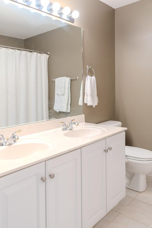 full bathroom with tile patterned flooring, double vanity, toilet, and a sink