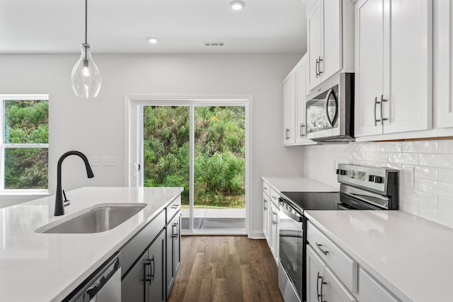 kitchen with backsplash, stainless steel appliances, light countertops, and a sink