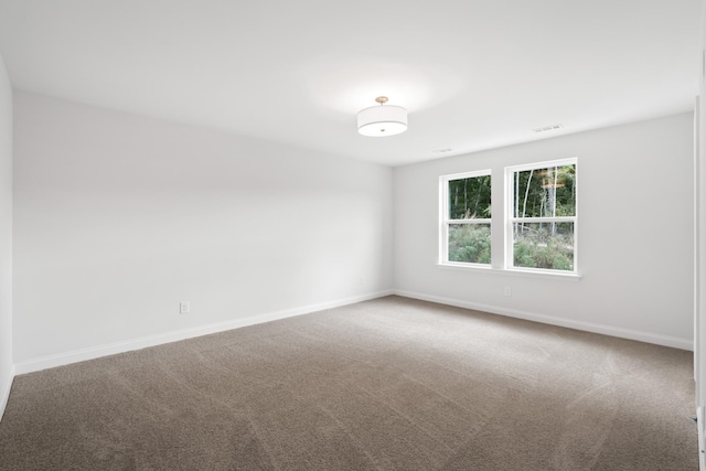 empty room featuring carpet flooring, visible vents, and baseboards