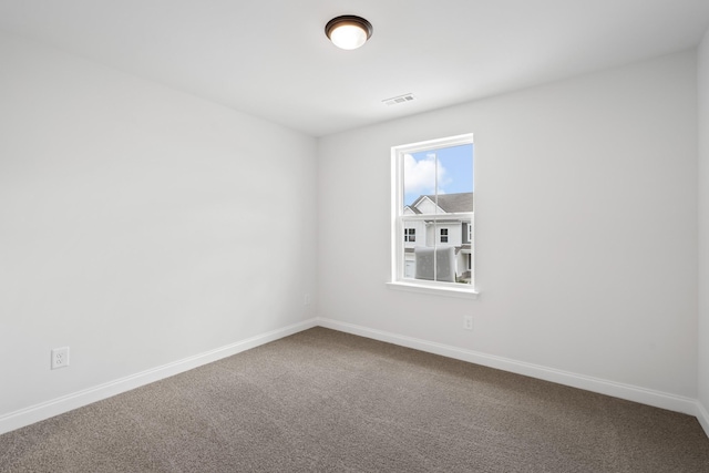 spare room featuring visible vents, dark carpet, and baseboards