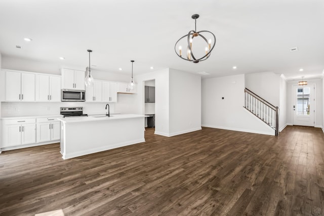 kitchen featuring a kitchen island with sink, a sink, dark wood-style floors, open floor plan, and appliances with stainless steel finishes