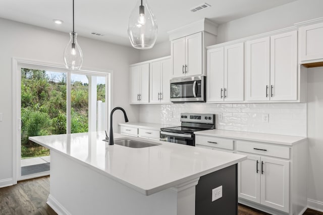 kitchen featuring a center island with sink, visible vents, a sink, appliances with stainless steel finishes, and tasteful backsplash