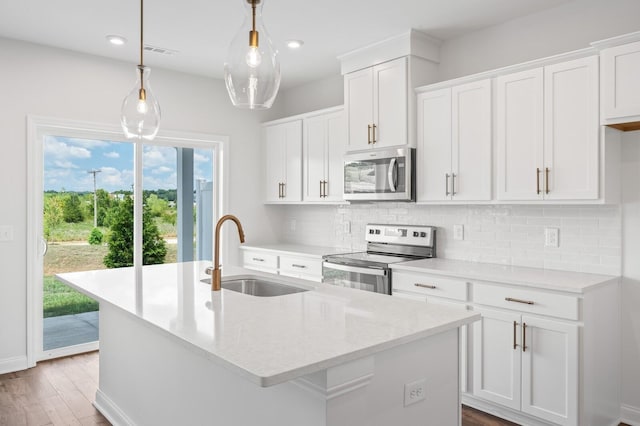 kitchen with visible vents, an island with sink, a sink, appliances with stainless steel finishes, and backsplash