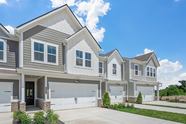 view of property with stone siding, board and batten siding, concrete driveway, and an attached garage