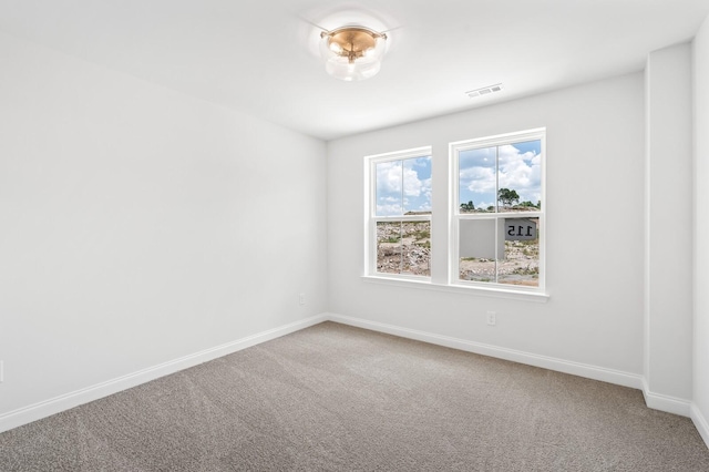 carpeted spare room featuring visible vents and baseboards