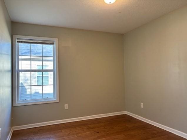 spare room featuring dark wood finished floors and baseboards