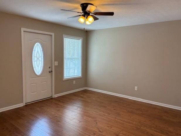 entryway with ceiling fan, dark wood-type flooring, and baseboards