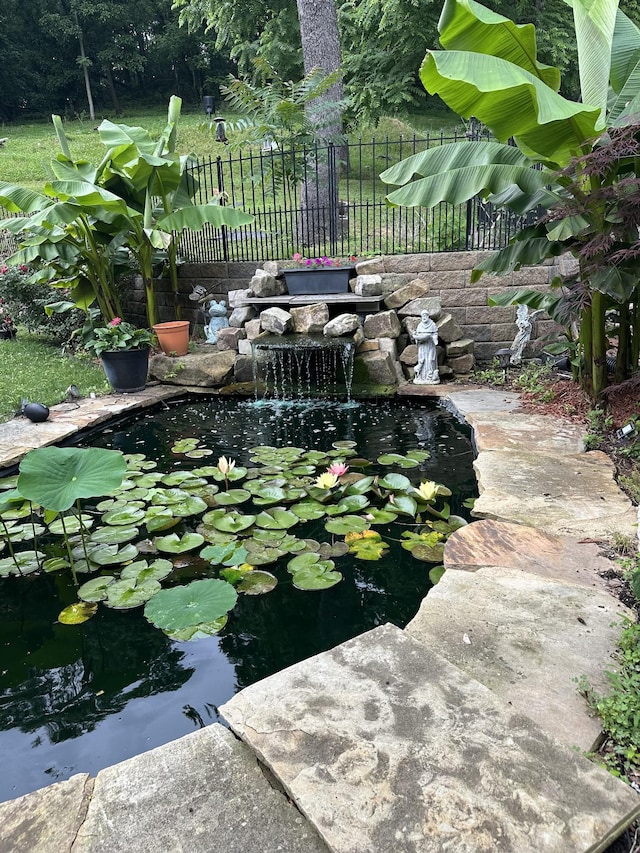 view of yard featuring a garden pond and fence