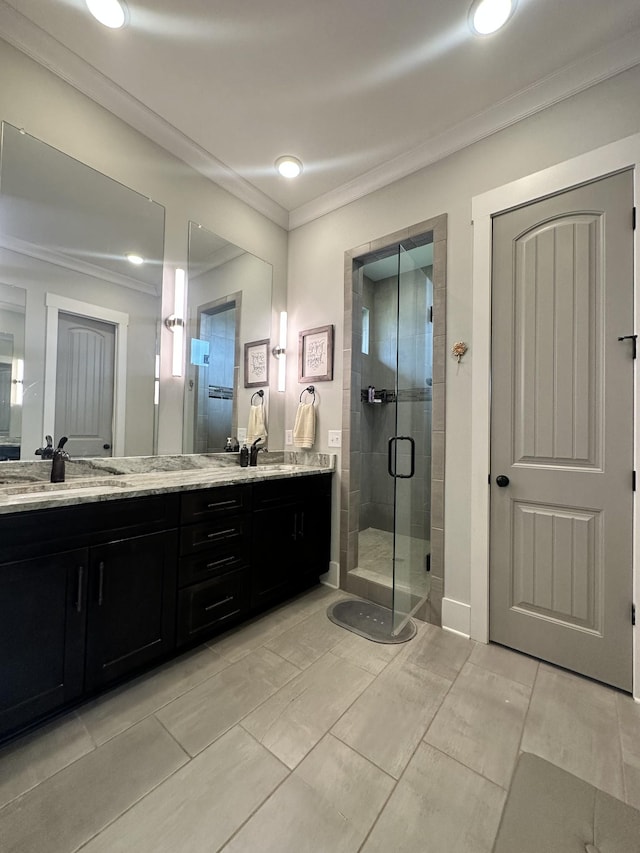 bathroom with double vanity, a shower stall, crown molding, and a sink