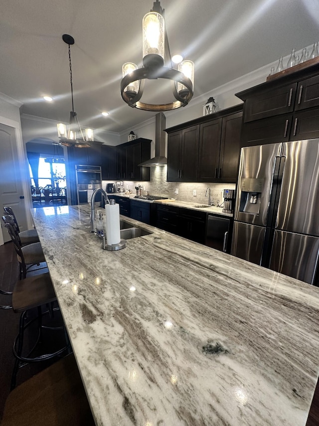 kitchen with wall chimney range hood, ornamental molding, appliances with stainless steel finishes, and a sink