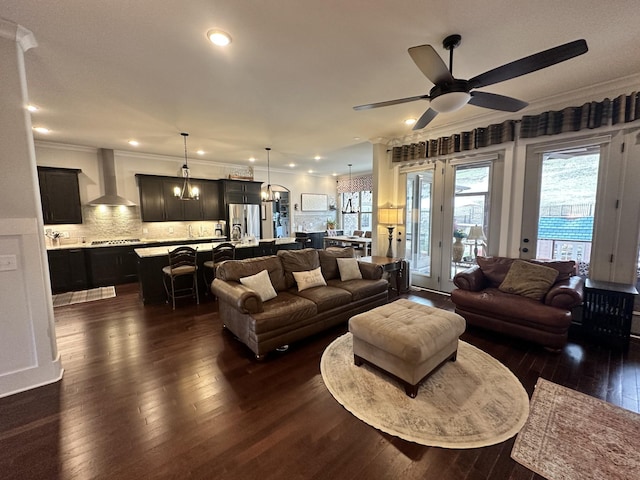 living area featuring recessed lighting, dark wood finished floors, crown molding, and ceiling fan with notable chandelier