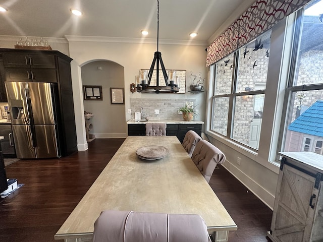 dining room featuring arched walkways, dark wood-style flooring, and ornamental molding