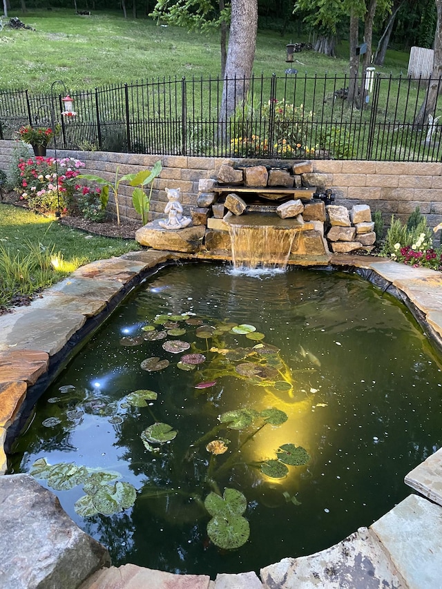 view of home's community featuring a small pond and fence