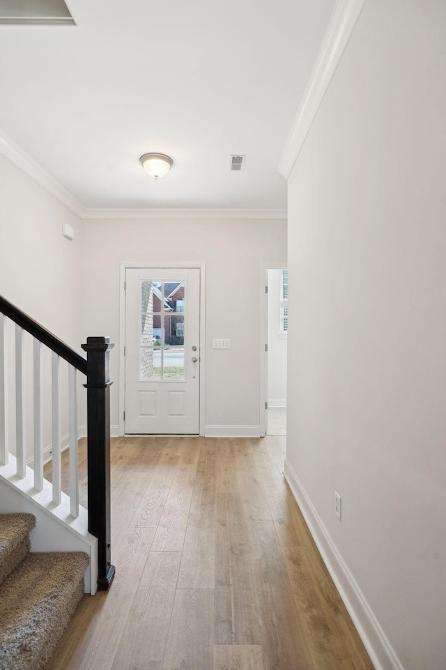 entryway featuring stairway, visible vents, light wood finished floors, and ornamental molding