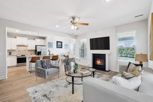 living room with visible vents, light wood-style flooring, recessed lighting, ceiling fan, and a glass covered fireplace