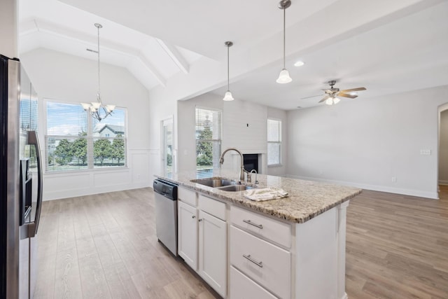 kitchen with light wood-style flooring, a sink, open floor plan, white cabinetry, and appliances with stainless steel finishes