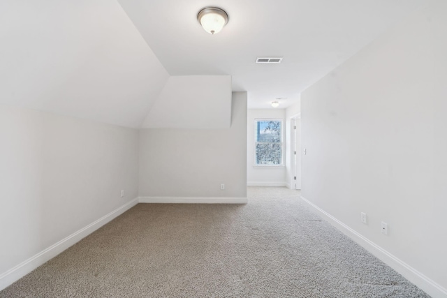 additional living space featuring lofted ceiling, baseboards, visible vents, and carpet floors