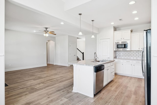 kitchen with open floor plan, backsplash, stainless steel appliances, and a sink