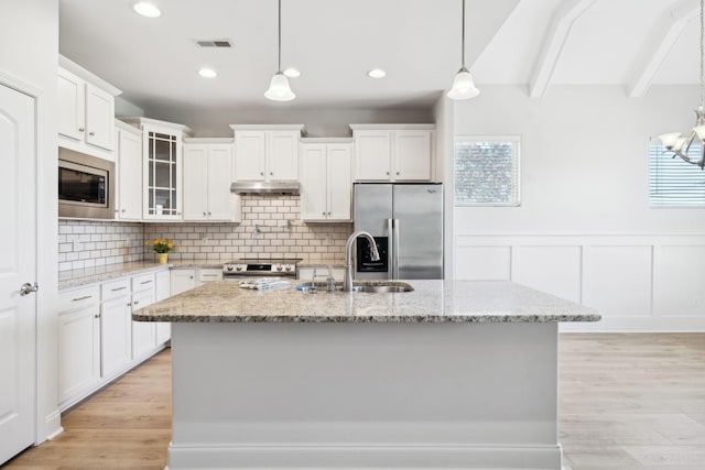 kitchen with visible vents, under cabinet range hood, beam ceiling, stainless steel appliances, and a sink