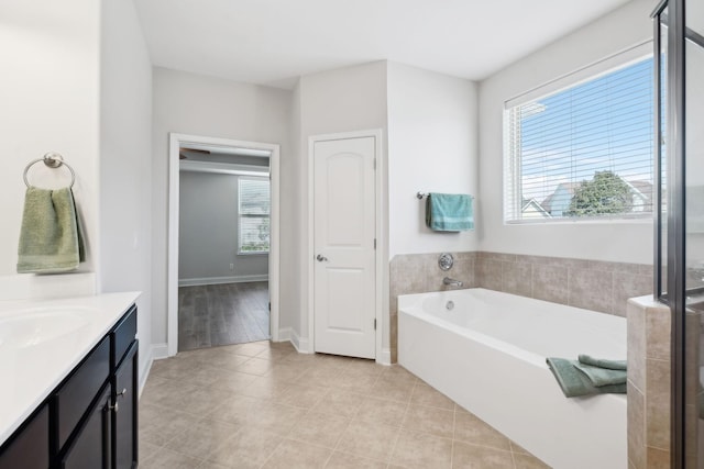 bathroom featuring a healthy amount of sunlight, a bath, vanity, and tile patterned flooring