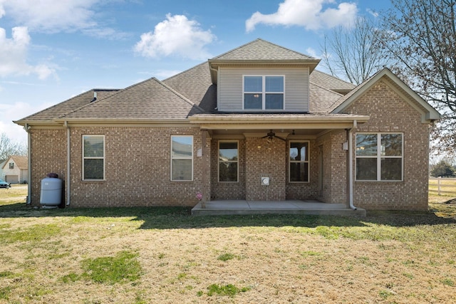 rear view of house featuring a yard, ceiling fan, brick siding, and a patio