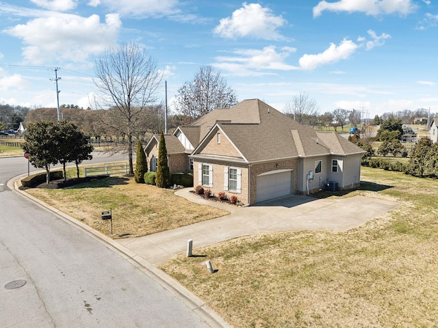 traditional home with driveway, brick siding, an attached garage, and a front lawn