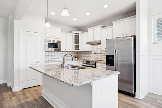 kitchen featuring a sink, under cabinet range hood, light wood-style floors, appliances with stainless steel finishes, and white cabinets