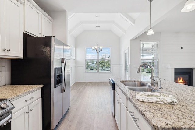 kitchen with lofted ceiling, white cabinets, stainless steel appliances, and a sink