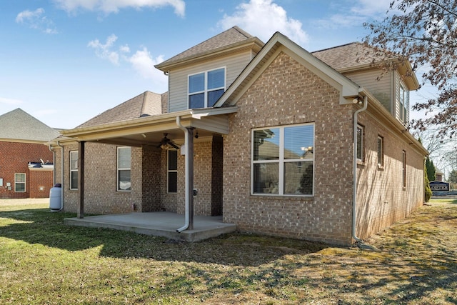 rear view of property featuring a patio, a yard, a ceiling fan, and brick siding