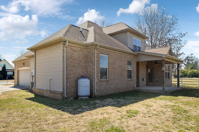 back of property featuring a lawn, a ceiling fan, fence, roof with shingles, and a garage