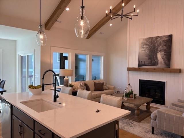 kitchen with a sink, light countertops, dishwasher, beamed ceiling, and open floor plan