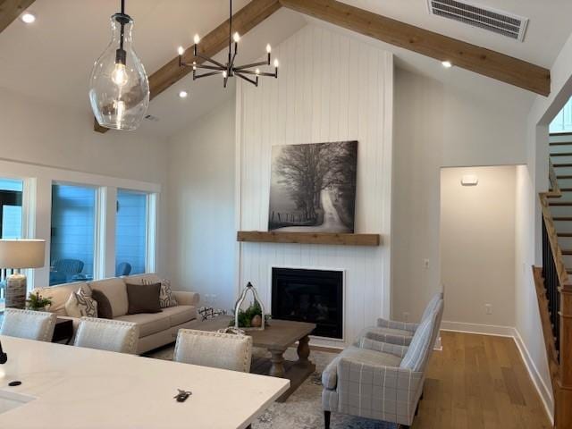 living area featuring stairway, wood finished floors, visible vents, high vaulted ceiling, and beamed ceiling