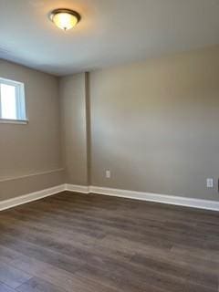 spare room with baseboards and dark wood finished floors