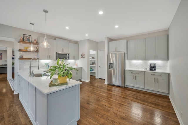 kitchen with a sink, open shelves, appliances with stainless steel finishes, a peninsula, and light countertops