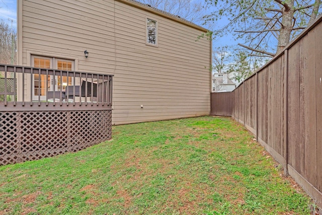 back of property featuring a yard, a wooden deck, and a fenced backyard