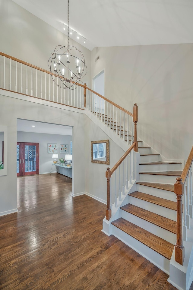 staircase featuring visible vents, high vaulted ceiling, wood finished floors, an inviting chandelier, and baseboards