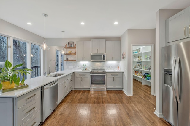 kitchen featuring a sink, open shelves, appliances with stainless steel finishes, light countertops, and decorative backsplash