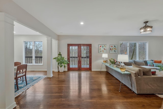 living area with a wealth of natural light, baseboards, ornate columns, and wood finished floors