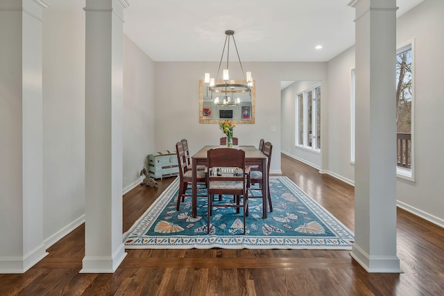 dining space featuring baseboards, ornate columns, and wood finished floors