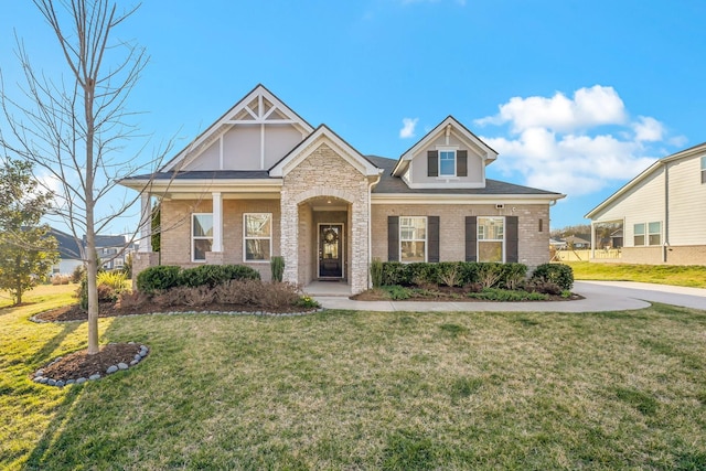 craftsman house featuring a front yard, brick siding, and stone siding