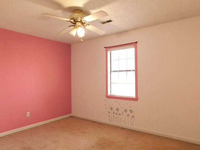 spare room featuring visible vents, baseboards, ceiling fan, light colored carpet, and a textured ceiling